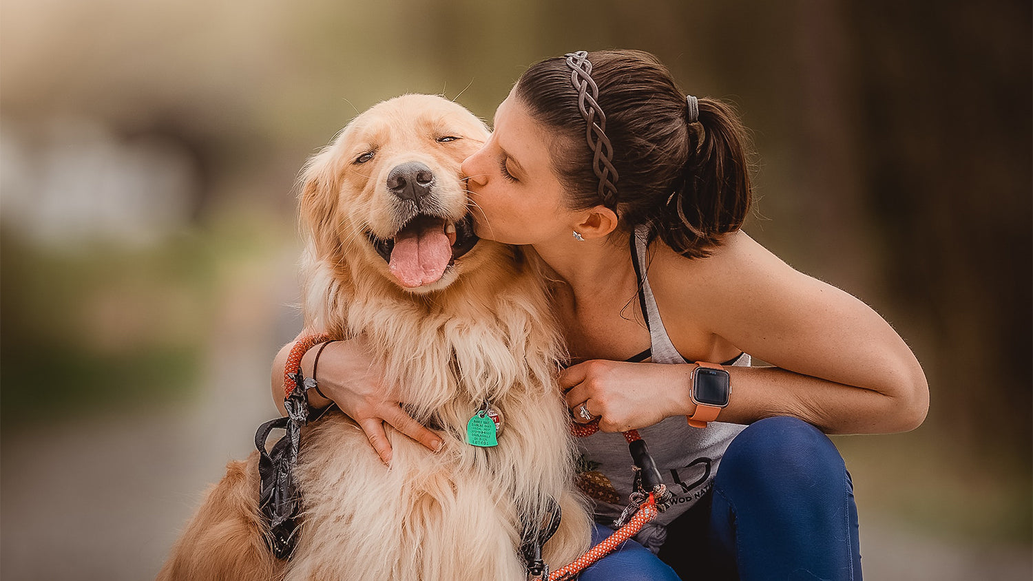 Ein Hund wird von seiner Besitzerin geküsst und sieht dabei sehr glücklich aus.